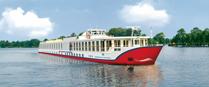 Die MS KATHARINA VON BORA fährt ruhig auf dem Fluss. Sanftes Licht spiegelt sich auf dem Wasser, während die Landschaft vorbeizieht.