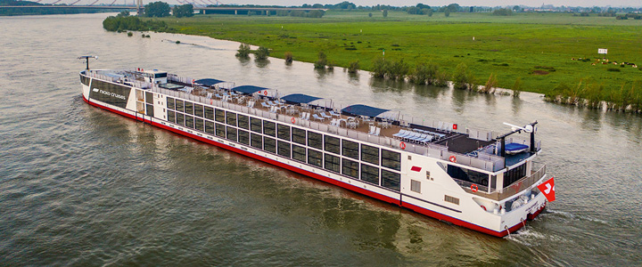 Die nickoSPIRIT gleitet im warmen Abendlicht über den Rhein. Grüne Wiesen säumen das ruhige Ufer der vorbeiziehenden Landschaft.