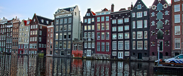 Typische Grachtenhäuser säumen die Wasserwege Amsterdams. Das ruhige Wasser spiegelt Fassaden und das weiche Licht der Stadt.